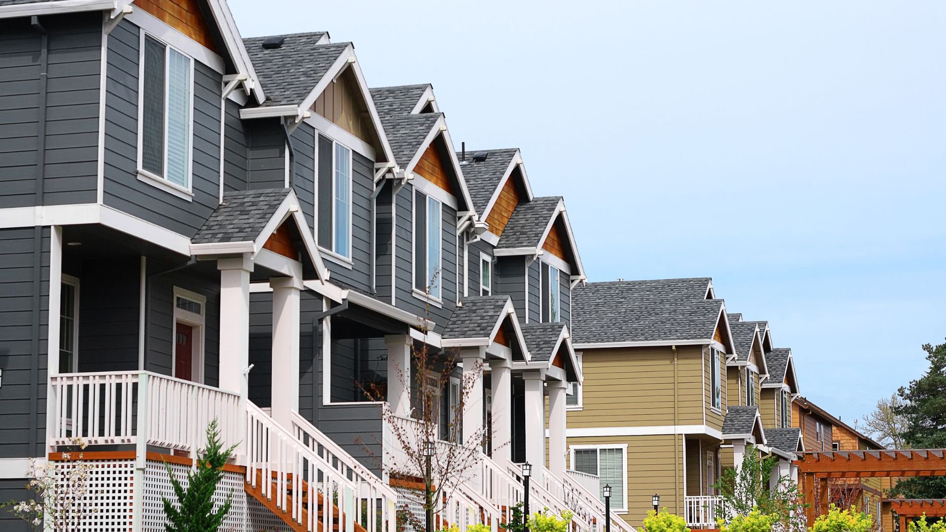 Row of modern townhouses with gray and yellow siding and white railings