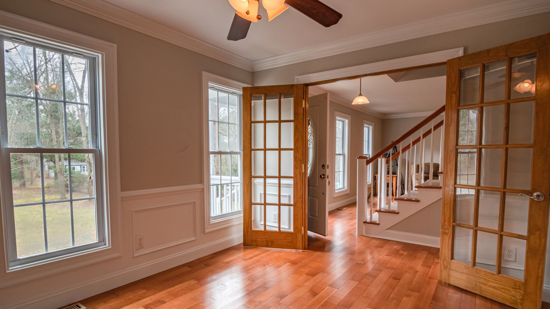 Bright interior with hardwood floors, French doors, and staircase