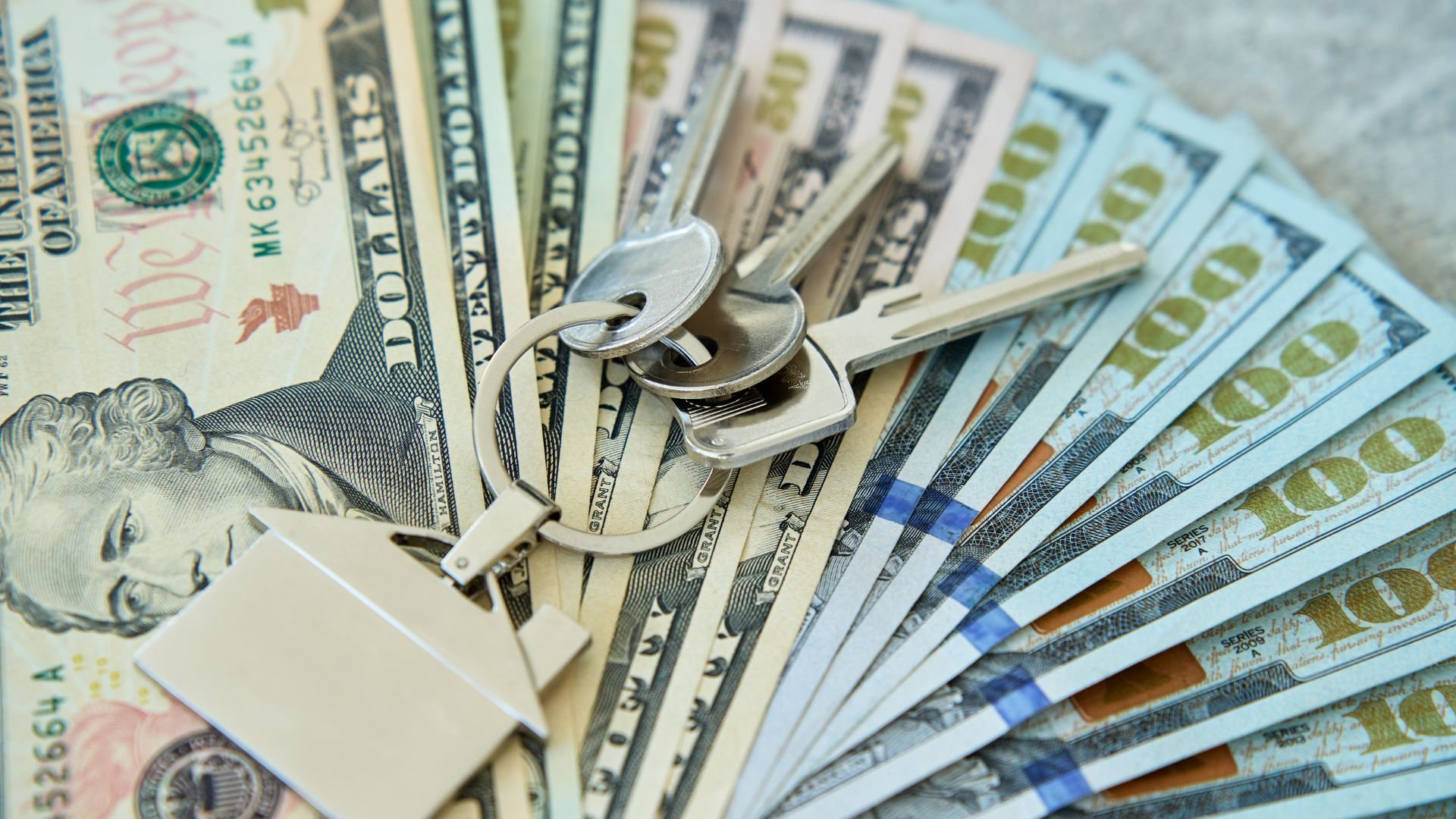 Keys and padlock resting on spread out US dollar bills