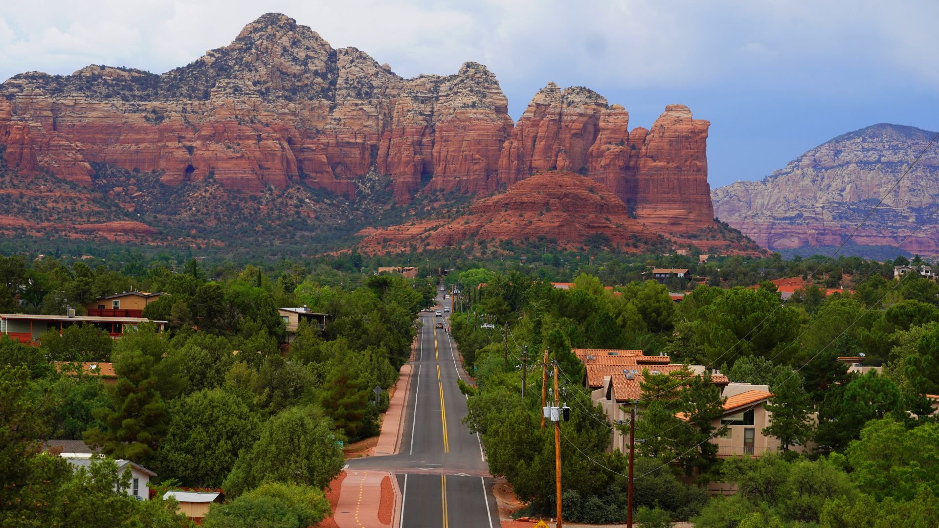Sedona's scenic road leading through green trees towards red rock mountains